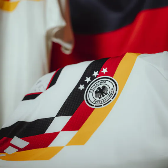 Detailaufnahme eines Deutschland-Trikots mit DFB-Wappen und farbigen Designelementen.